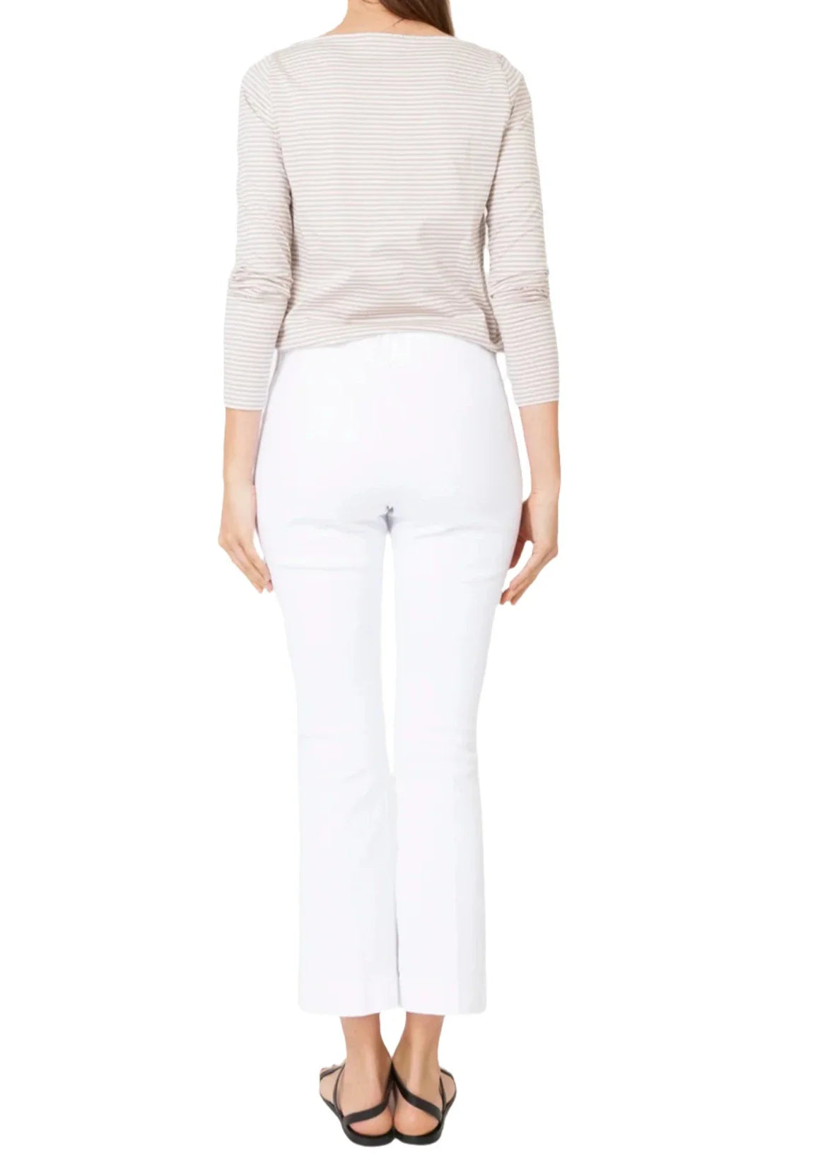 A person wearing a beige striped long-sleeve top, Ann Mashburn Faye Flare Cropped Stretch Twill Pant, and black sandals is seen from the back.