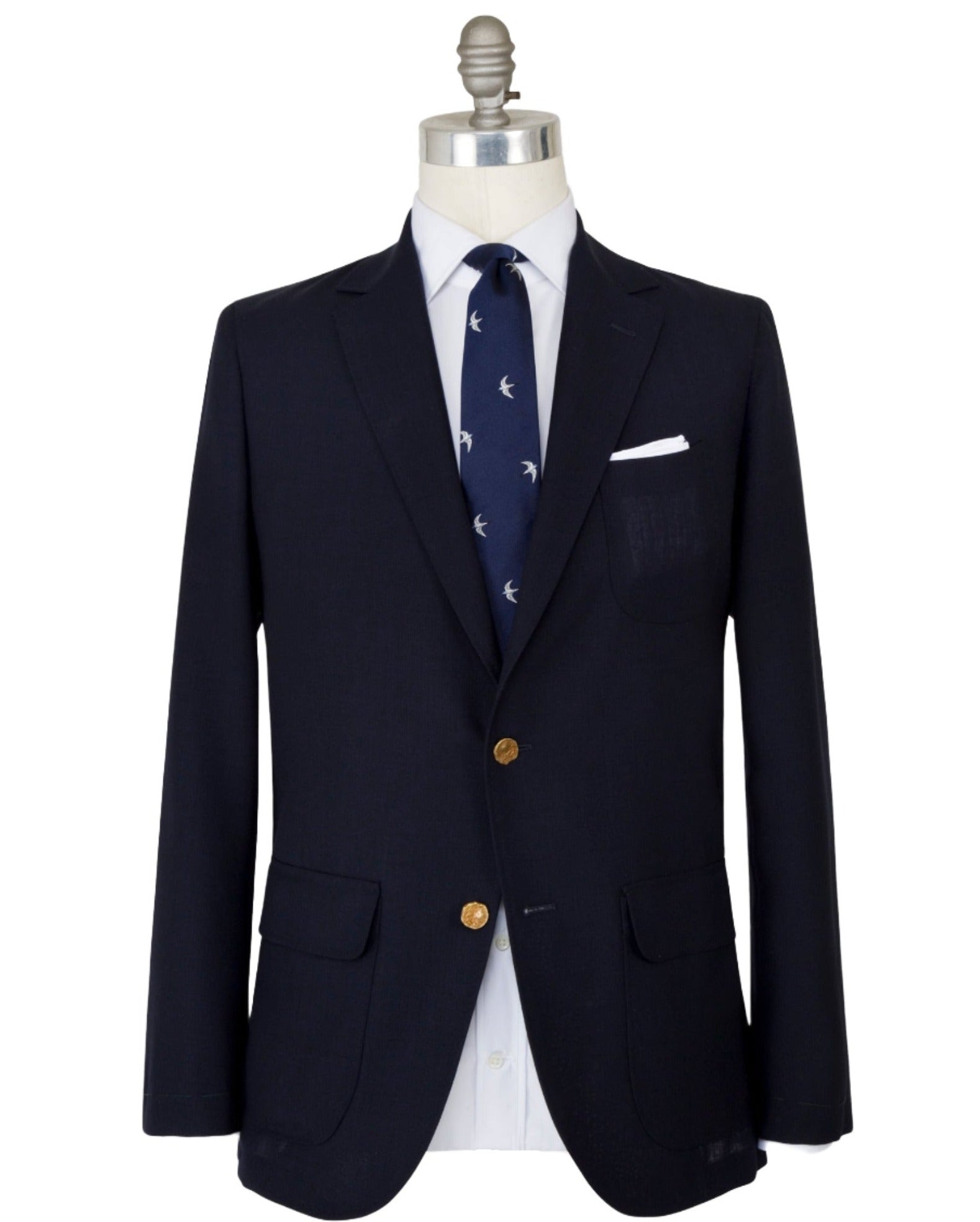 Mannequin dressed in a Sid Mashburn Ghost Blazer with unlacquered brass buttons, a white dress shirt, a navy tie with white bird patterns, and a white pocket square.