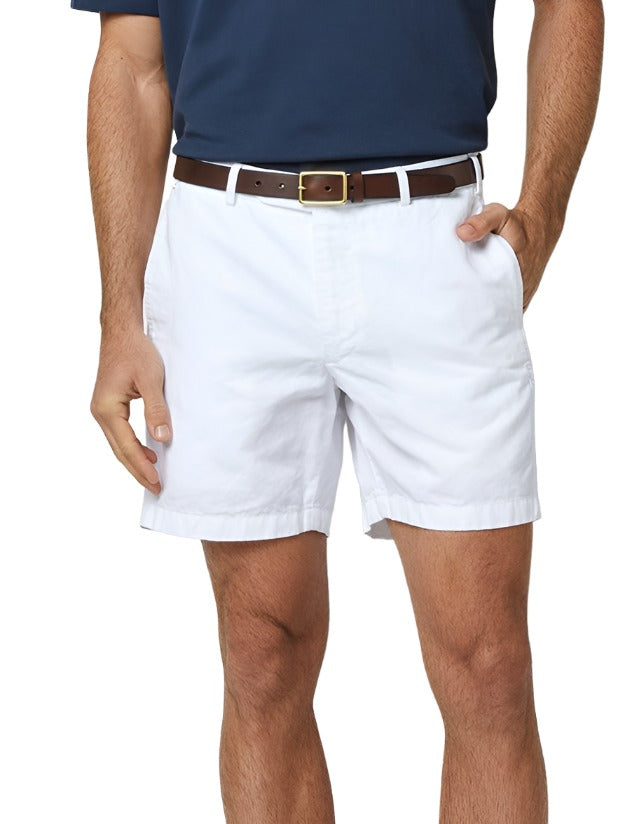 A person wearing Sid Mashburn Garment Dyed Sport Short with a 7" inseam, a brown belt, and a navy blue shirt, with one hand in their pocket. The lightweight cotton twill fabric and garment-dyed finish add to the casual yet stylish look.