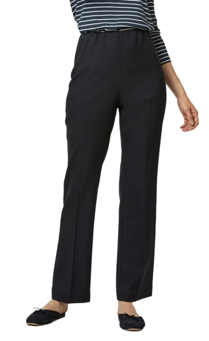 A person wearing a black and white striped top and the Ann Mashburn Alice Pant, polished flared pants made of seasonless stretch wool from the brand Ann Mashburn, paired with black shoes, stands against a plain background.