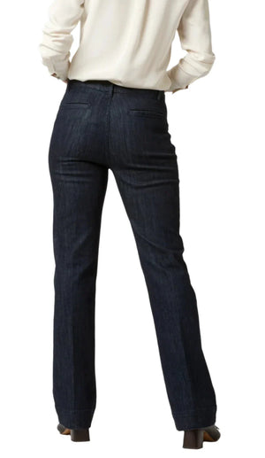 A person wearing a white long-sleeve shirt and a pair of Ann Mashburn Sloane Trouser Jeans in dark blue with a 32" inseam is standing with their back to the camera.