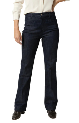 Individual wearing a white long-sleeve shirt and Ann Mashburn Sloane Trouser Jean in dark blue stretch denim with a 32" inseam, standing against a white background.