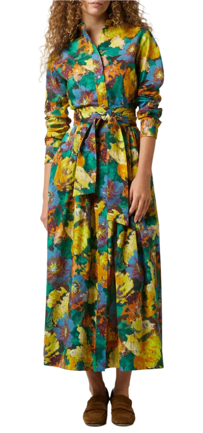 A person wearing the Ann Mashburn Classic Shirtwaist Maxi Dress LS with a vibrant floral pattern and an accompanying belt, standing with their hands by their sides.