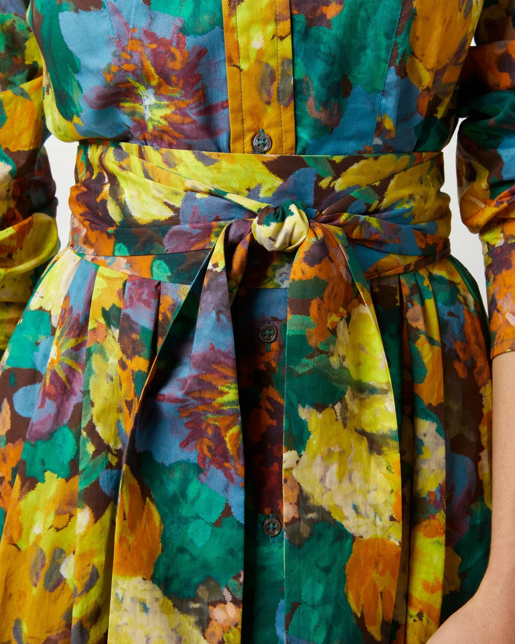 Close-up of the Ann Mashburn Classic Shirtwaist Maxi Dress LS, featuring a waist-tied silhouette with short sleeves and a vibrant multicolored floral pattern. The dress showcases button details and pleats in a classic shirtwaist style by Ann Mashburn.