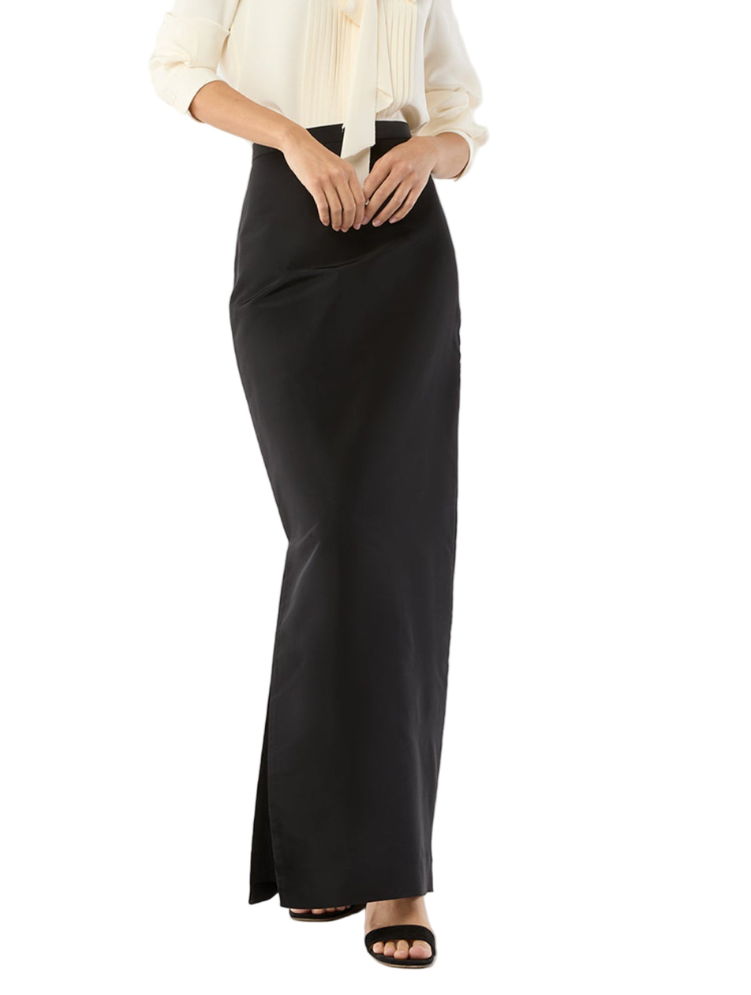 A person wears a cream long-sleeve silk blouse and the Ann Mashburn Long Pencil Silk Faille Skirt in black, paired with open-toe black sandals, standing against a white background.