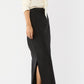 A woman wearing the Ann Mashburn Long Pencil Silk Faille Skirt with a cream silk blouse and black heeled sandals stands against a plain white background.