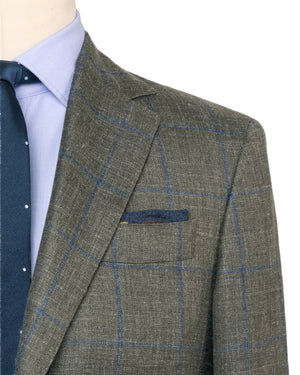 Close-up of a person wearing the Sid Mashburn Virgil No. 2 Jacket in grey plaid silk and linen, paired with a light blue dress shirt and a navy tie with small white dots.