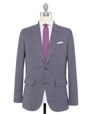 The Sid Mashburn Ghost Blazer in gray Italian hopsack is displayed on a mannequin, styled with a white dress shirt, purple patterned tie, and white pocket square.