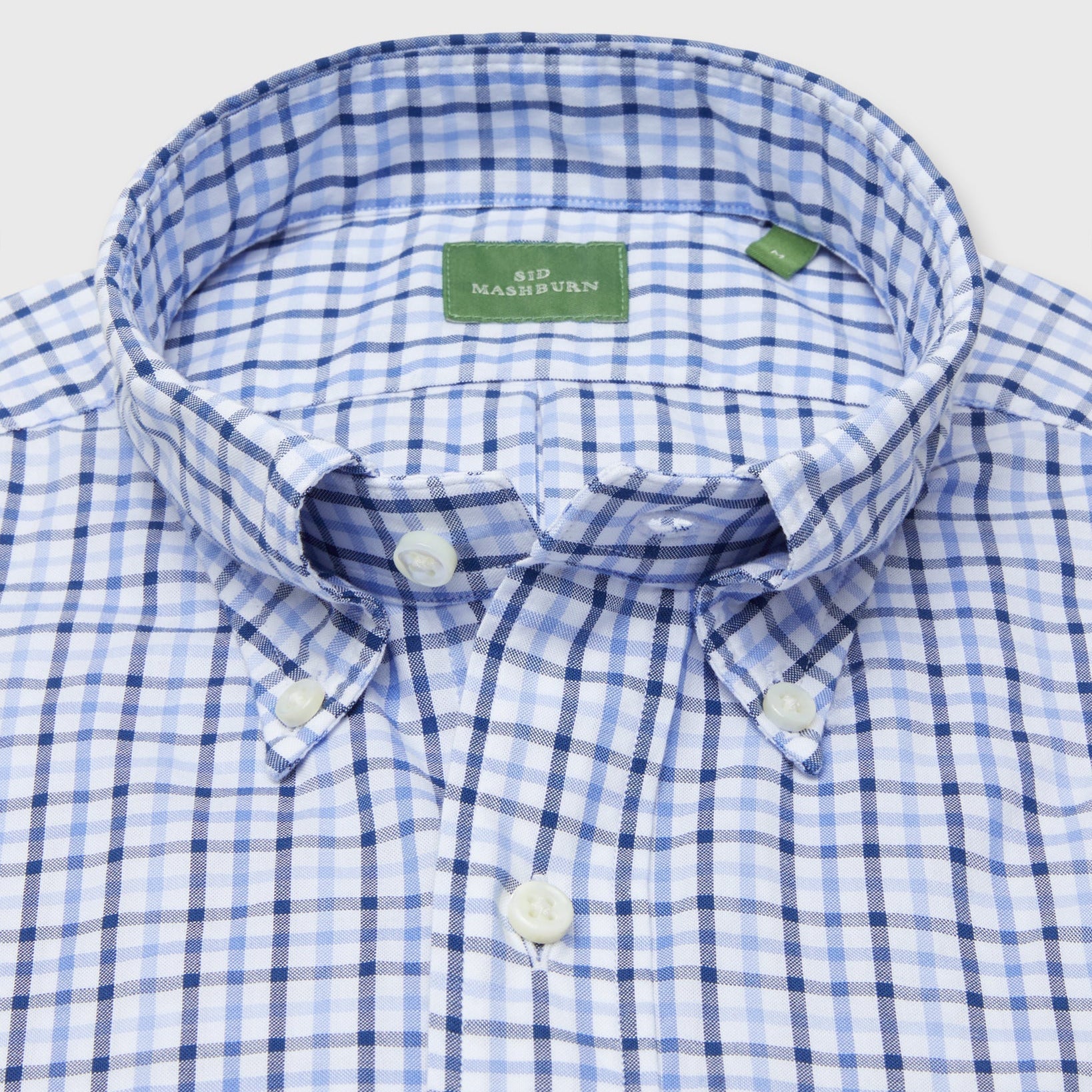 Close-up of a blue and white plaid Sid Mashburn Button-Down Sport Shirt in a slim fit, featuring an oxford weave, button-down collar, and green "SID MASHBURN" label inside.