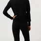 A person stands with one hand on their hip, wearing the Ann Mashburn Rosie Cotton Silk Cardigan and black pants, photographed from the back against a plain background.
