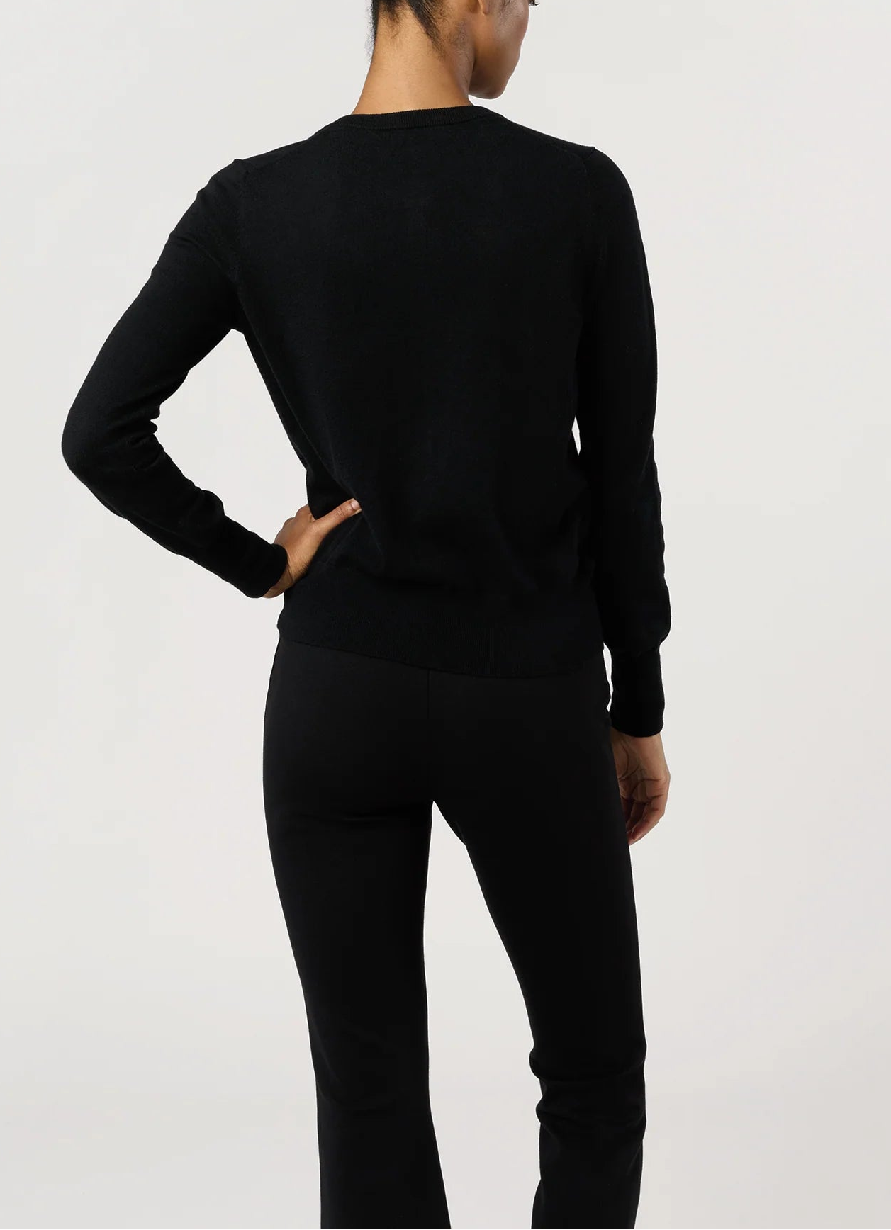 A person stands with one hand on their hip, wearing the Ann Mashburn Rosie Cotton Silk Cardigan and black pants, photographed from the back against a plain background.