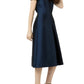 A woman wears the Ann Mashburn Suzzette Dress—a navy blue, cap-sleeve, midi A-line dress—paired with black high-heeled sandals.