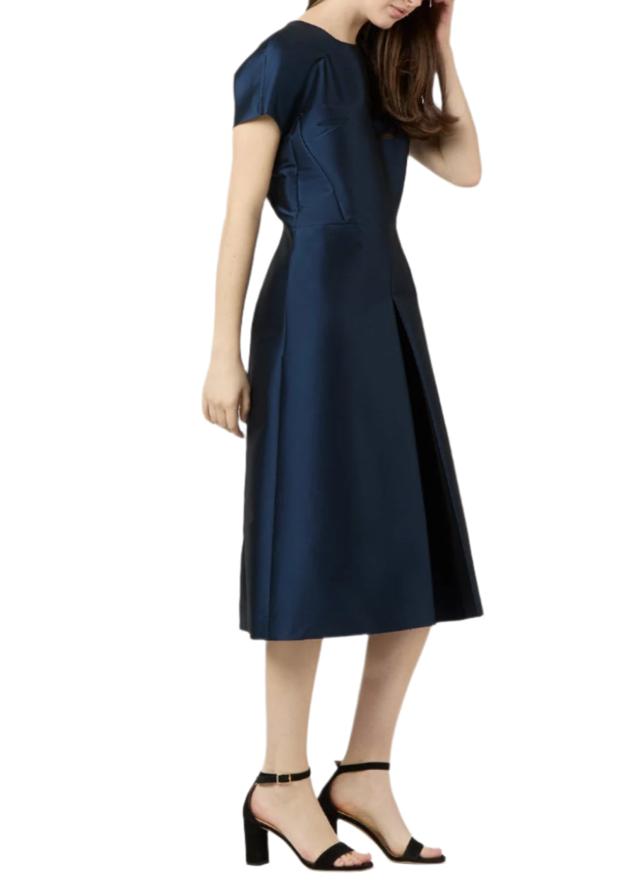 A woman wears the Ann Mashburn Suzzette Dress—a navy blue, cap-sleeve, midi A-line dress—paired with black high-heeled sandals.