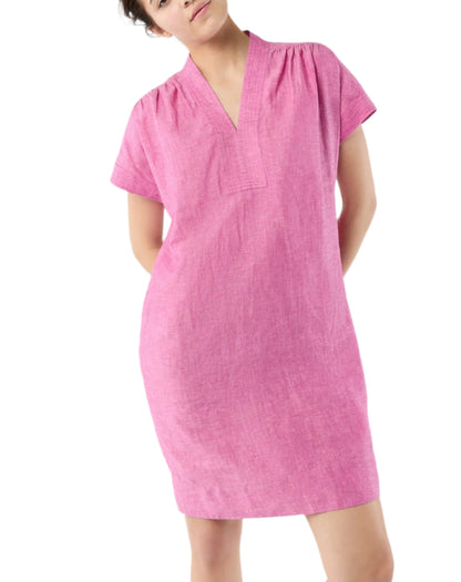 A model wears the Ann Mashburn Libby Dress—a loose, short-sleeve, knee-length pink dress with a V-neckline—against a plain white background.