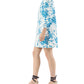 A person in the Ann Mashburn Francine Dress, featuring white faille with blue florals, and black wedge sandals, stands in profile against a white background.