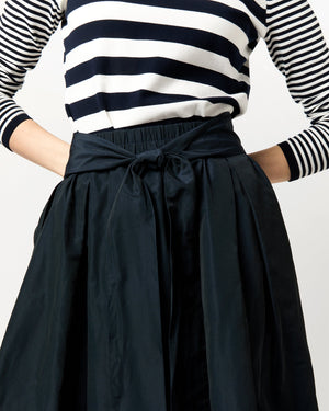 Model wears a high-waisted black Ann Mashburn Carla Skirt with an elastic waist, paired with a black and white striped long-sleeve shirt, shown from shoulders to knees.