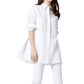 A woman wearing the Ann Mashburn Gabrielle Tie Tunic in white Italian poplin with rolled-up sleeves and white pants, standing against a plain background.