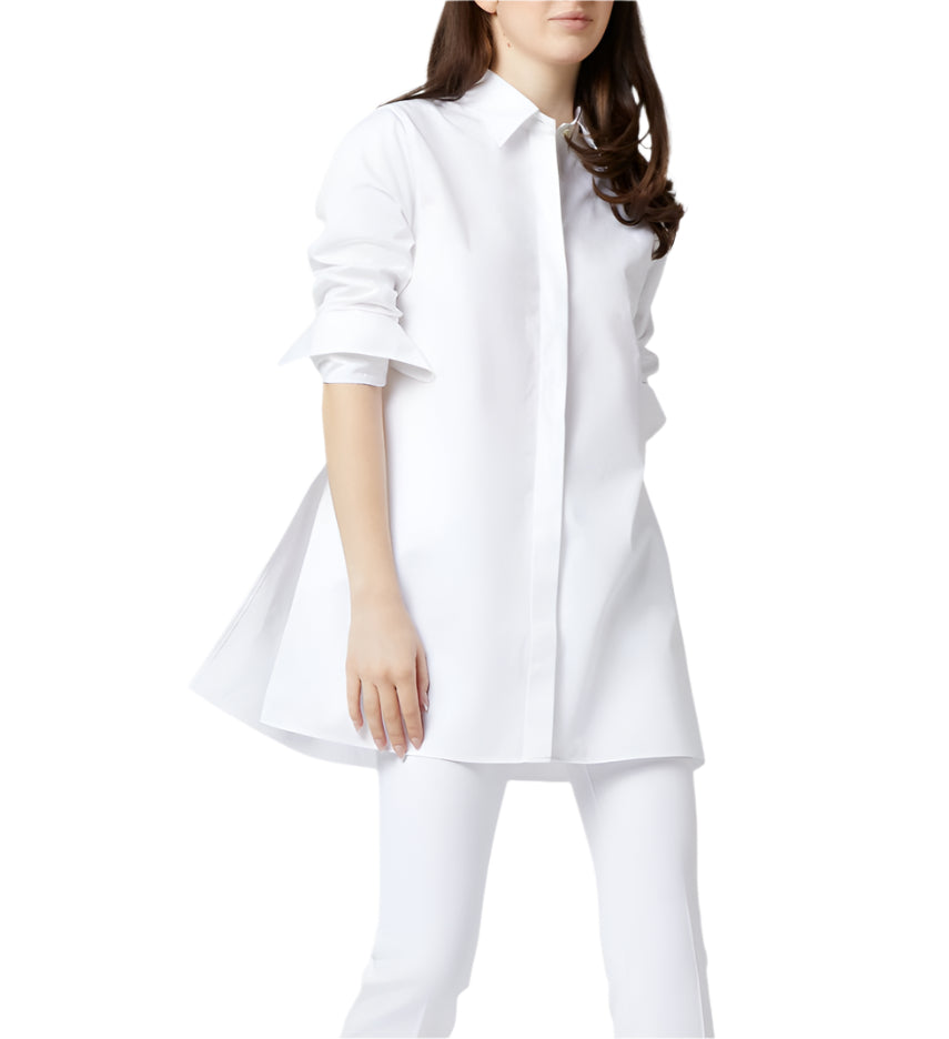 A woman wearing the Ann Mashburn Gabrielle Tie Tunic in white Italian poplin with rolled-up sleeves and white pants, standing against a plain background.