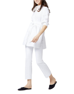 Someone wearing the Ann Mashburn Gabrielle Tie Tunic with white pants and black slip-on shoes walks against a plain background.