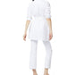 A woman stands with her back to the camera, wearing the Ann Mashburn Gabrielle Tie Tunic in white Italian poplin, accented at the waist, paired with white slim-fit pants and black flats against a white background.
