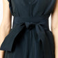 A person models Ann Mashburn's Gigi Dress, an A-line style in dark blue with trapunto stitching and a wide belt tied in a bow, accentuating the upper body and arms.