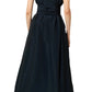 The person is wearing the Gigi Dress by Ann Mashburn, an elegant black ankle-length dress with short sleeves and a wrap belt, featuring subtle trapunto stitching, viewed from behind.
