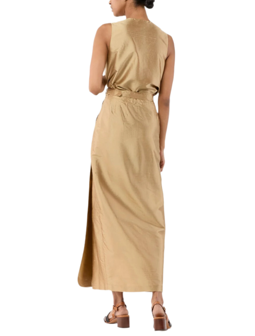 A person wearing the Ann Mashburn Renata Silk Shantung Wrap Skirt, an ankle-length tan skirt with a side slit and column silhouette, paired with brown sandals and shown from the back.