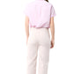 A person stands with their back to the camera in a light pink Ann Mashburn Agnes Shirt, featuring short sleeves and Trocas shell buttons, tucked into high-waisted white pants against a plain white background.