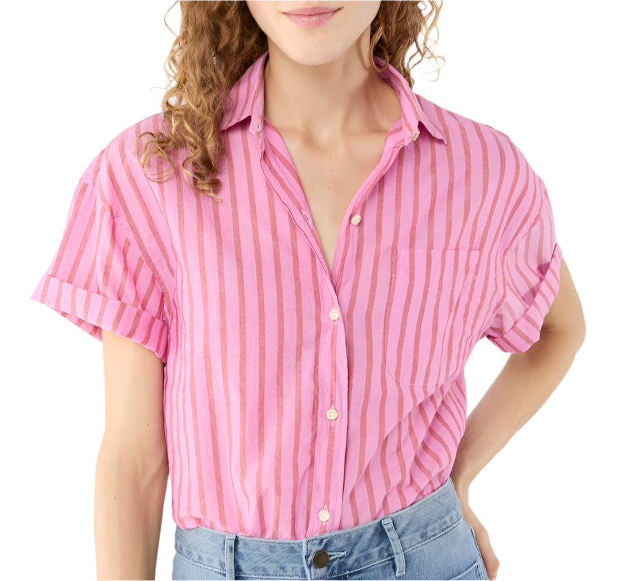Someone is wearing the Ann Mashburn Agnes Shirt—a pink and red vertically striped, oversized short-sleeve button-up with Trocas shell buttons—paired with light blue jeans.