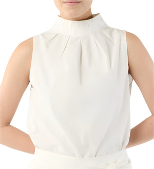 A person wearing the Ann Mashburn Clair Top, a white sleeveless mock neck tank with a high pleated neckline, stands with hands behind their back.
