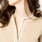 A woman with long brown hair wears the Aubrey Cardigan by Ann Mashburn, showcasing hand-crocheted trim and white buttons, facing slightly left against a plain backdrop.