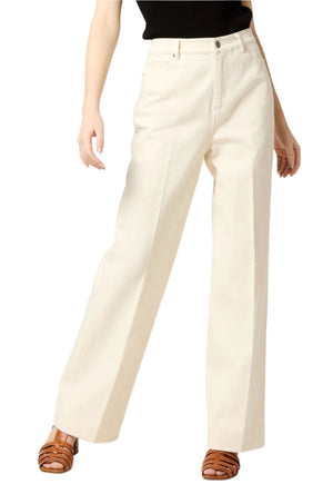 Wearing a tomboyish outfit, someone styles their look with cream-colored Coco Jean wide-leg pants by Ann Mashburn and brown strappy sandals.