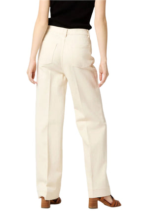 A person is styled in Ann Mashburn's Coco Jean, cream-colored wide-legged pants with a straight column leg, paired with brown heeled sandals, viewed from the back.