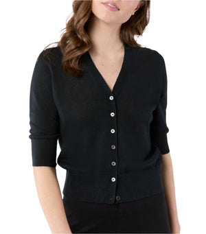 A woman wearing the Ann Mashburn Rosie Cardigan, a black linen button-up with a V neckline and elbow-length sleeves, stands against a white background.