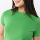 A person with long dark hair wears the Ann Mashburn Lee Tee, a fitted green short-sleeve t-shirt. The image highlights the shirt’s body-hugging fit on the upper torso against a plain background.
