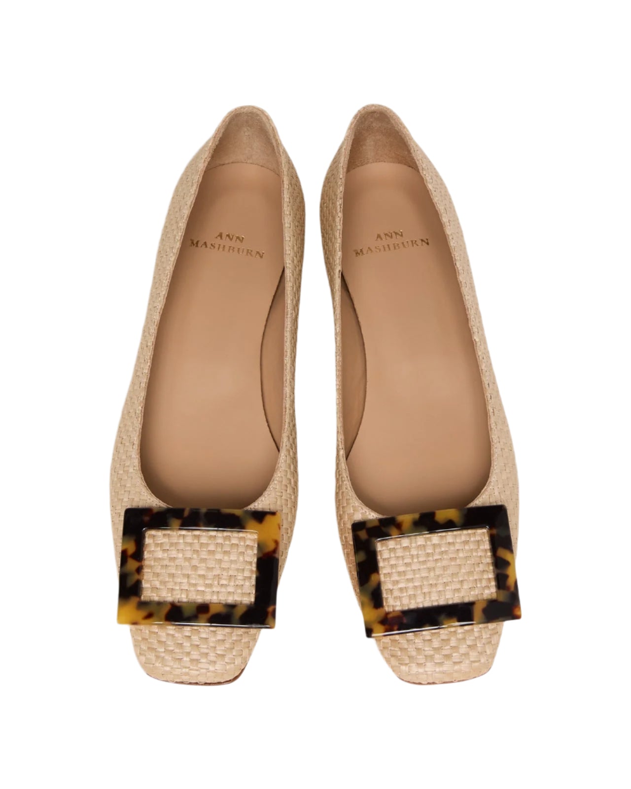 The Ann Mashburn Buckle Basketweave Shoe is a pair of beige woven flats with square tortoiseshell buckles on the toes, inspired by 1960s style and shown from above.