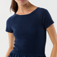 A woman in the Ann Mashburn Cosette Cotton Silk Dress, a short-sleeved ribbed navy blue knit with round neck, styled with a gathered poplin skirt.