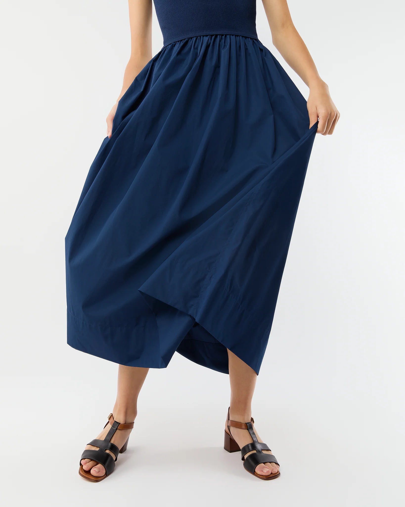 Model wearing the Ann Mashburn Cosette Cotton Silk Dress, holding the sides to showcase its fullness against a plain background.