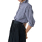 A person wears the Ann Mashburn Weekender Shirt in blue and white checks, tucked into a dark high-waisted pleated skirt. The relaxed silhouette stands out against a plain white background.