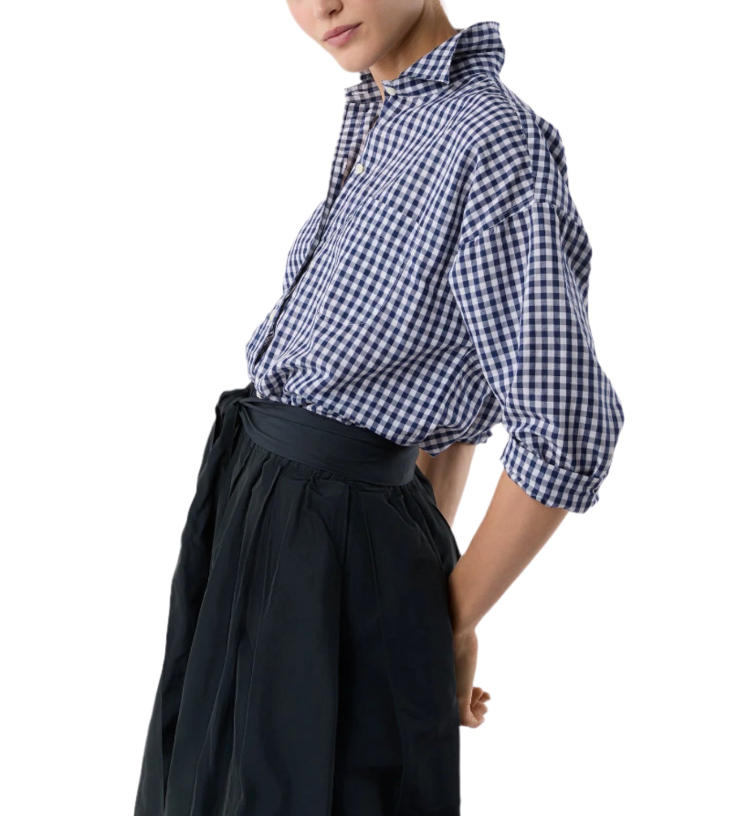 A person wears the Ann Mashburn Weekender Shirt in blue and white checks, tucked into a dark high-waisted pleated skirt. The relaxed silhouette stands out against a plain white background.