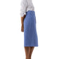 A woman stands in profile wearing a white long-sleeve shirt, tan heeled sandals, and the Kara Wrap Skirt by Ann Mashburn—a high-waisted skirt with blue and white vertical stripes.
