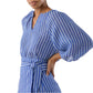 A woman in the Ann Mashburn Victoria Blouse—a blue and white striped top with balloon sleeves, romantic details, and a matching waist tie—stands with one hand on her hip.