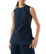 Someone wearing the Ann Mashburn Jo Bi-Stretch Tropical Wool Tunic, a sleeveless navy shell tank with princess seams, paired with matching pants and standing with one hand by their side.