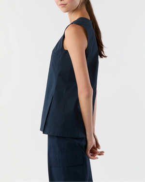 A woman stands sideways against a plain background, hands behind her back, wearing the Ann Mashburn Jo Bi-Stretch Tropical Wool Tunic and matching navy pants.