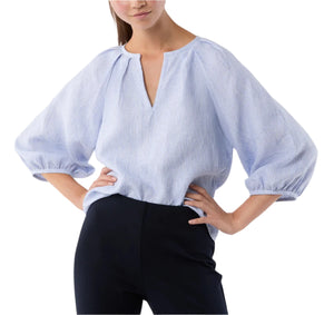 A person wearing the Ann Mashburn Victoria Small Bengal Stripe Linen Blouse—light blue stripes, billowy Belgian linen with balloon sleeves—and black pants, stands with hands on hips; ideal for spring and summer.
