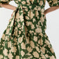 A close-up of the Allegra Dress by Ann Mashburn, a green seersucker style with beige floral prints, a tied waist belt, and a ruffled tiered skirt.
