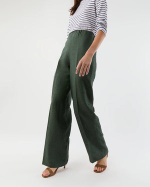 A person wears a white and black striped long-sleeve top, Ann Mashburn’s Maureen Pant in Italian linen with a straight roomy fit, and brown heeled sandals, standing against a plain background.