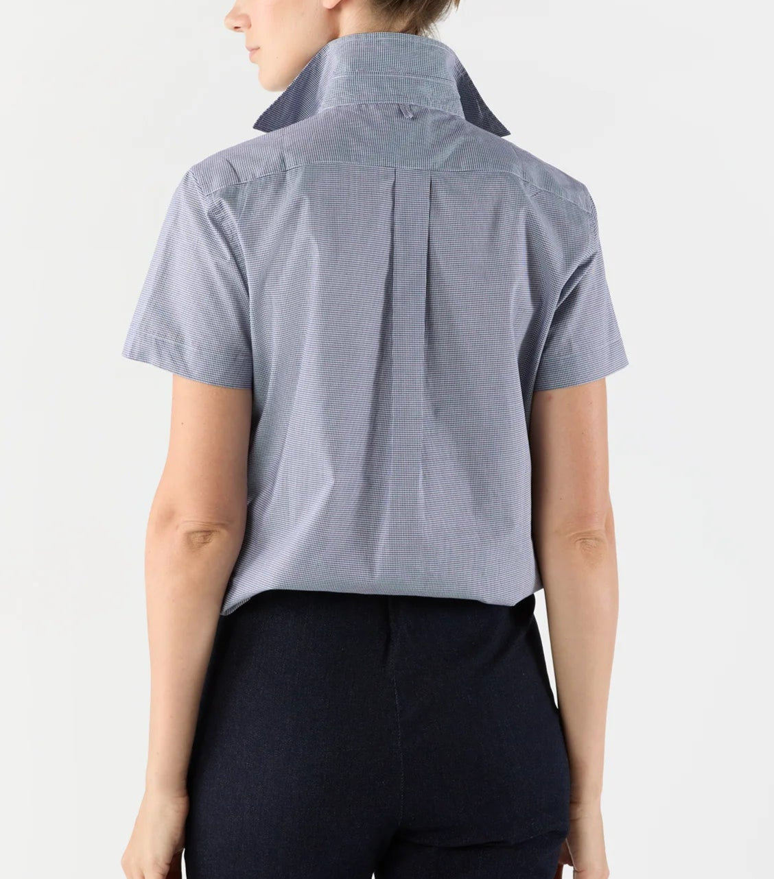 A person wearing an Ann Mashburn Scout Poplin Shirt in light blue, short-sleeve, with the collar popped, viewed from the back.