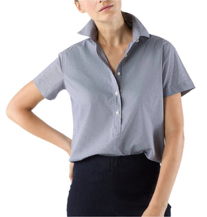 A person wears the Ann Mashburn Scout Poplin Shirt in light blue with short sleeves and a popped collar, paired with dark pants, standing against a plain white background.