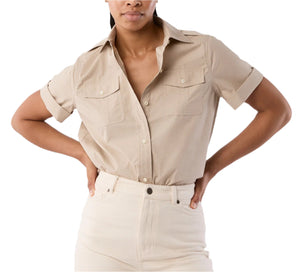 A person wears the Ann Mashburn Short Sleeved Poplin Safari Shirt, featuring front pockets, paired with high-waisted light pants and stands with hands on hips.